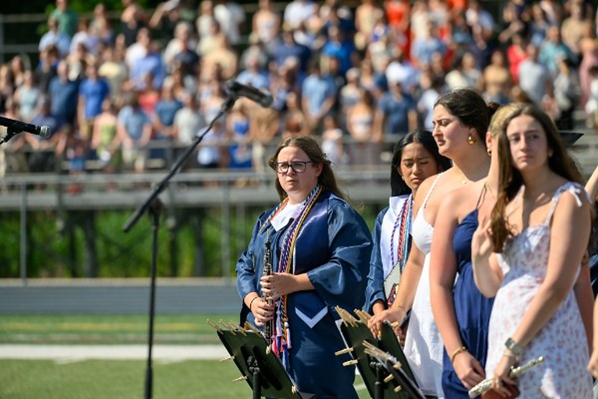 Ella holding her clarinet in cap and gown at her final band performance