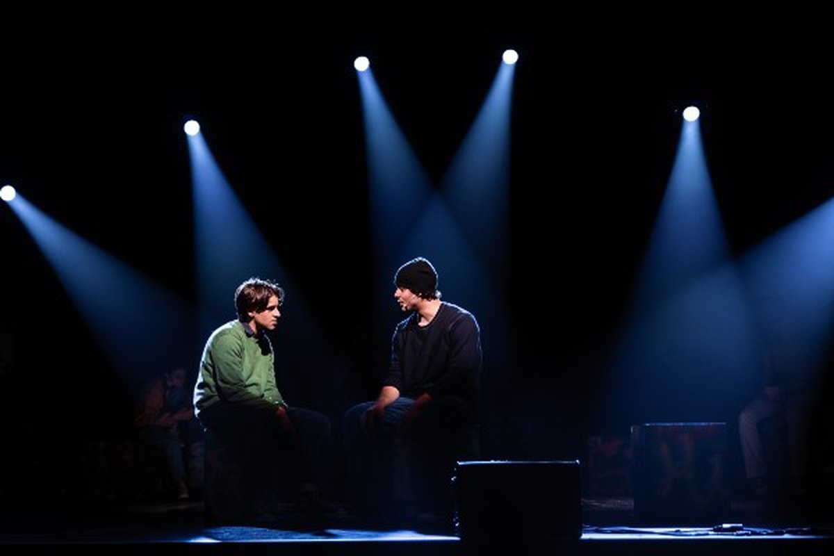 Two young actors seated in conversation under blue stage light during a performance of Lost Angels at the Count Basie Center for the Arts