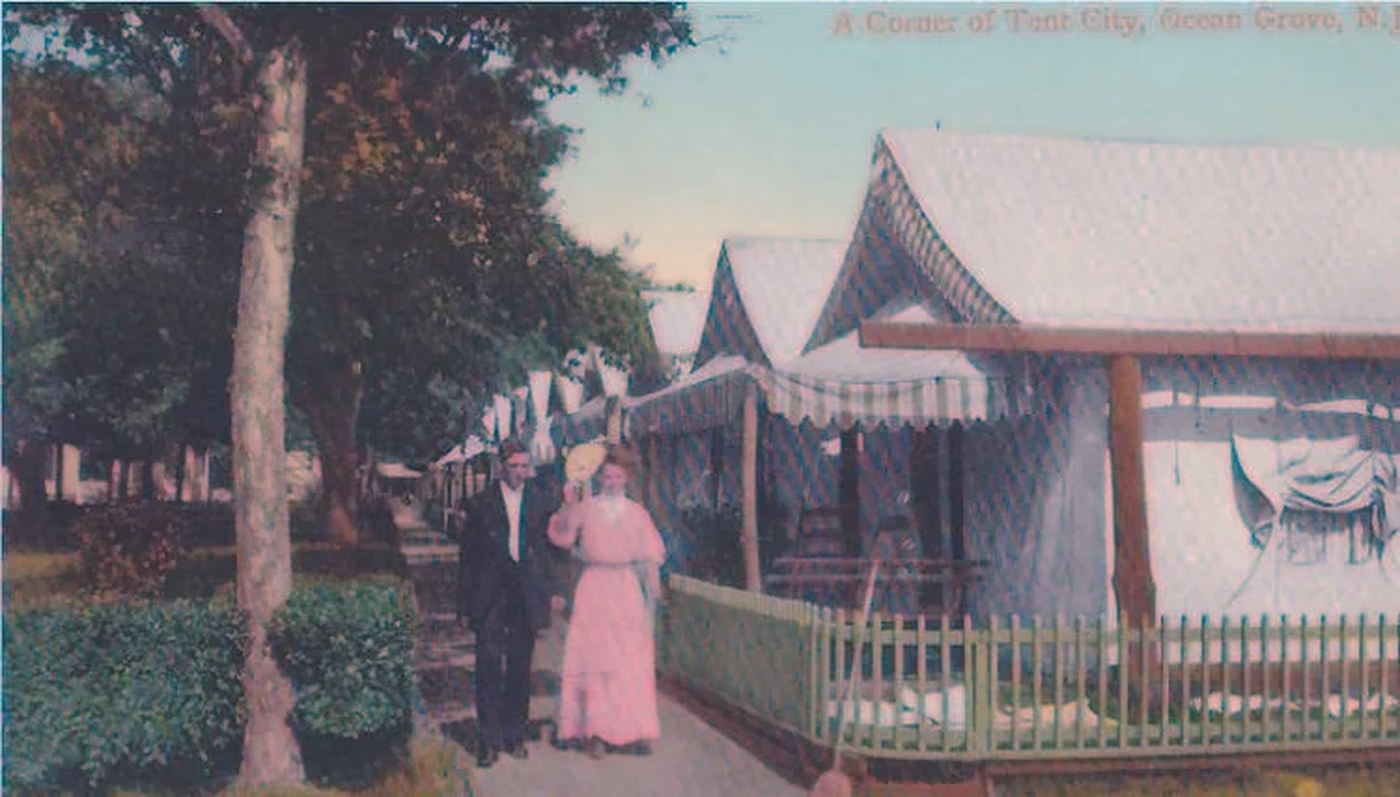 Vintage colorized postcard of a couple walking a tree-lined path through Ocean Grove's Tent City
