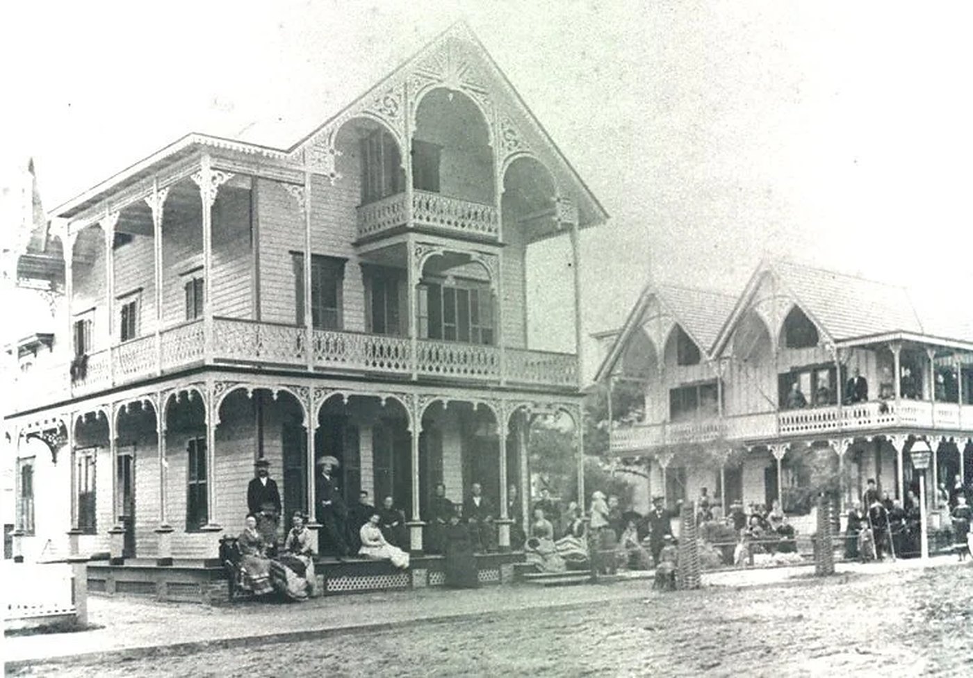 Black-and-white historical photograph of Ocean Grove's Victorian houses with ornate porches and gathered residents